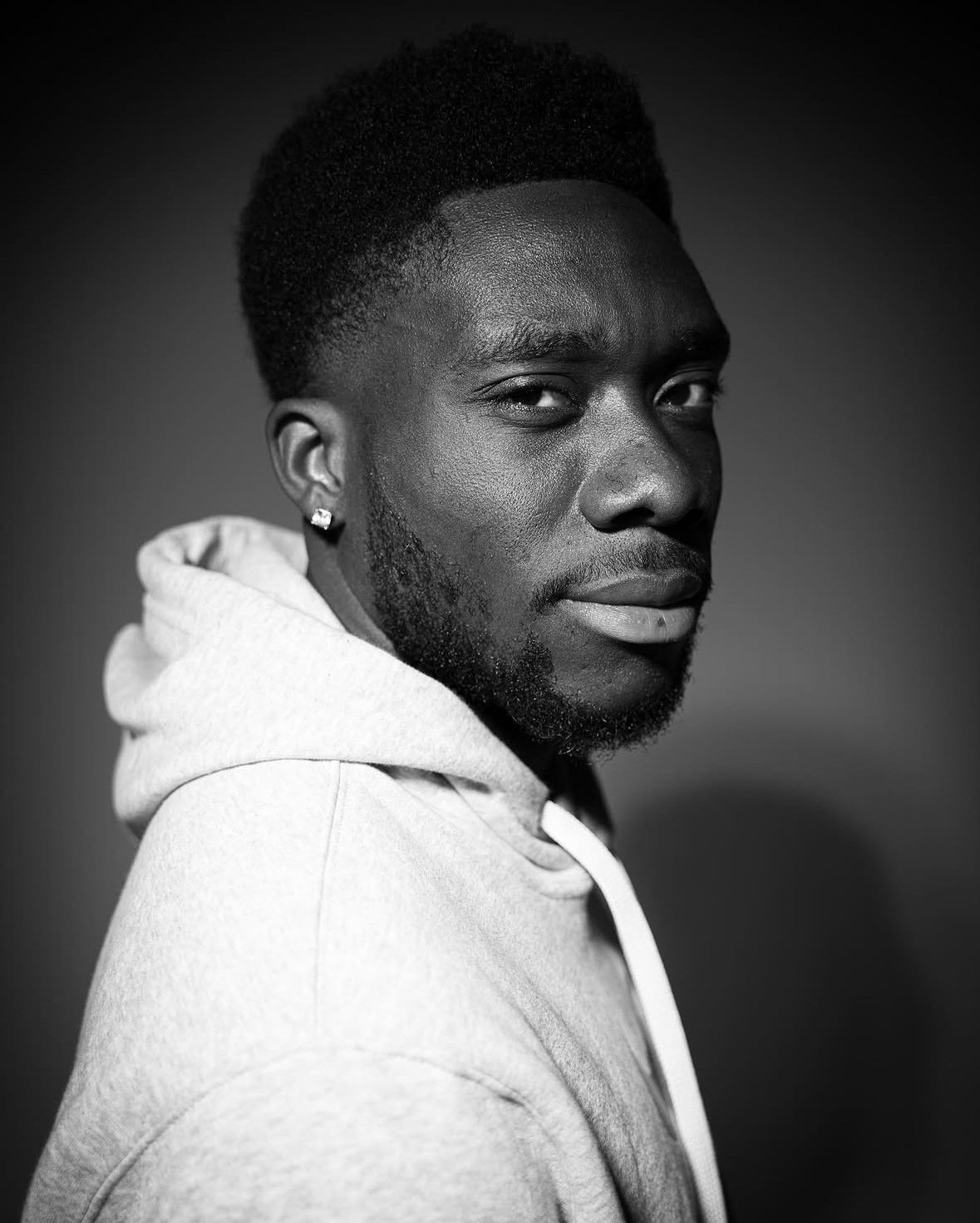 Black-and-white portrait of Alphonso Davies in a white hoodie