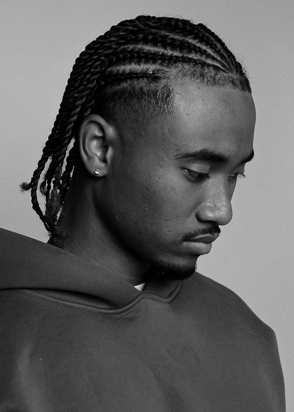 Black-and-white portrait of Dylan Sinclair with braids looking down